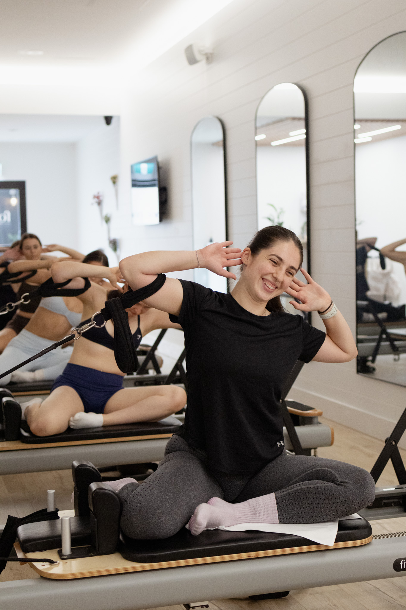 A smiling member taking part in a Forma Reformer Pilates class